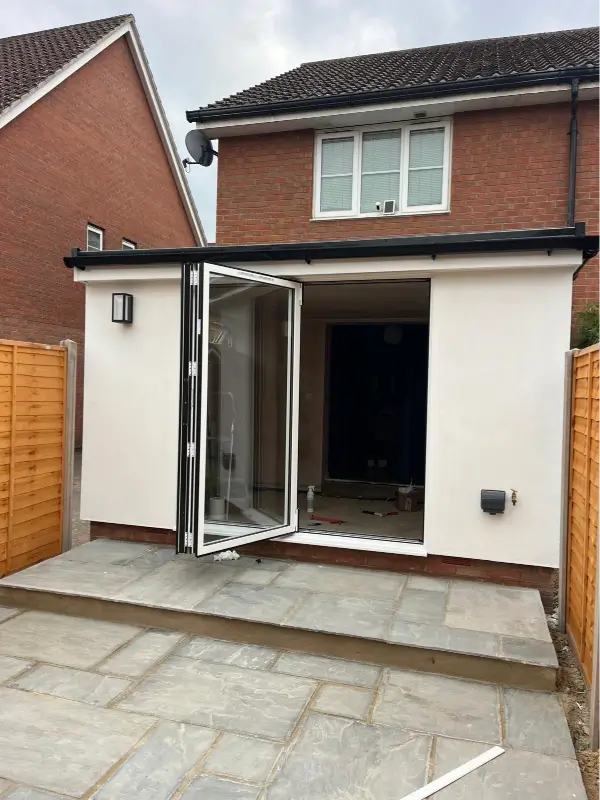 Completed Norwich HUP! extension with white render, dark roofline and open bifold doors